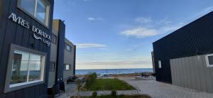 a black building with the ocean in the background at Ayres Dorados Lodge Hotel in Sierra Grande