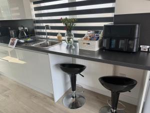 a kitchen with a counter with two stools and a sink at TomaX Garden Cabin Free Parking in Inverness +12 photos