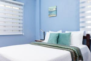 a blue bedroom with a bed with white sheets and blue walls at Ahra Suites First Floor with ocean view in Kingstown