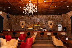 a restaurant with a bar with red chairs and a chandelier at Bissau Royal Hotel in Bissau