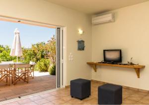 a living room with a sliding glass door with a table and a television at Seaside Aqua Bliss & Serenity with Private Pool in Kranidi