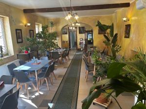 a restaurant with tables and chairs and plants at Zöldfa Panzió in Miskolc