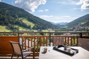a table and chairs on a balcony with a view at MGM Hôtels & Résidences - Résidence Chalets de Joy in Le Grand-Bornand