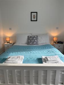 a white bed with blue sheets and towels on it at TomaX Garden Cabin Free Parking in Inverness