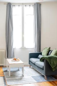 a living room with a blue couch and a table at Les Libournettes - Serenity in Libourne