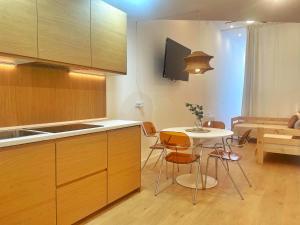 a kitchen with wooden cabinets and a table and a couch at Bosko Etxea Apartamentos in Bilbao