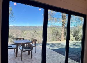 a table and chairs on a deck with a view at Yosemite Chalet, Spacious Tiny Home with Mountain Views! in Coarsegold