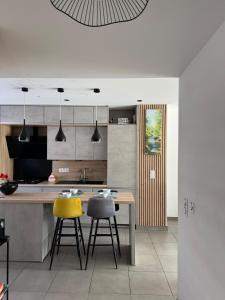 a kitchen with a table and two yellow bar stools at DAKEY home - Disneyland Paris, Village Nature in Magny-le-Hongre