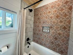 a bathroom with a tub and a tile wall at Yosemite Chalet, Spacious Tiny Home with Mountain Views! in Coarsegold +10 photos
