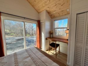 a bedroom with a desk and a bed and a window at Yosemite Chalet, Spacious Tiny Home with Mountain Views! in Coarsegold
