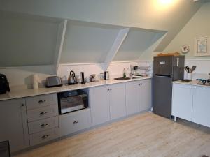 a kitchen with white cabinets and a refrigerator at Turquoise Loft, Noordhoek, Cape Town in Good Hope