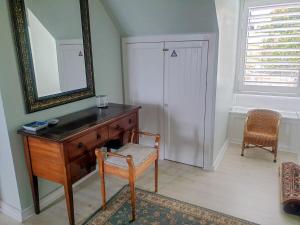 a dresser with a mirror and a chair in a room at Turquoise Loft, Noordhoek, Cape Town in Good Hope