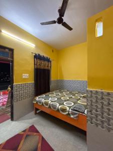 a bedroom with a bed in a room with yellow walls at Ambe hotel purnagiri in Tanakpur