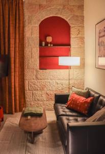 a living room with a leather couch and a brick wall at City Centre Gem - Machne Yehuda in Jerusalem +11 photos