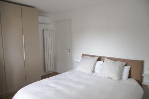 a bedroom with a bed with white sheets and pillows at Villa Serena - Luminor Apartment in Tirrenia