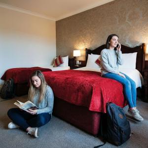 two girls sitting on beds in a hotel room at Killarney Riverside Hotel in Killarney