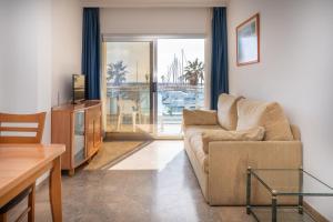 a living room with a couch and a television at Hotel Port Sitges in Sitges