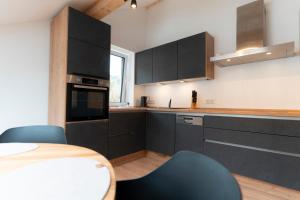 a kitchen with black cabinets and a table and chairs at SeeZeit Einruhr in Simmerath +9 photos