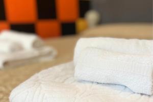 a stack of white towels sitting on a bed at Vicino Aeroporto - Orange Marina Room in Olbia
