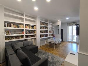a living room with a couch and a table and bookshelves at Downtown apartment in walk zone with 3 bedrooms and garage in Novi Sad