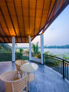 a table and chairs on a balcony with a view of the water at White Tree Apartment in Bentota