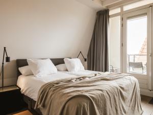 a white bedroom with a large bed with a window at Strandhotel Domburg in Domburg