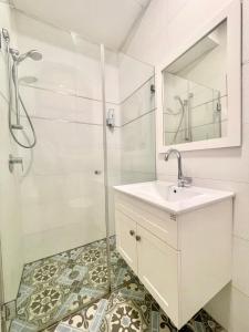 a white bathroom with a sink and a shower at Nachlaot Gem - Bright, Central and Cozy in Jerusalem