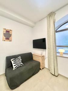 a living room with a couch and a flat screen tv at Nachlaot Gem - Bright, Central and Cozy in Jerusalem