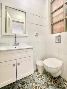 a white bathroom with a toilet and a sink at Nachlaot Gem - Bright, Central and Cozy in Jerusalem