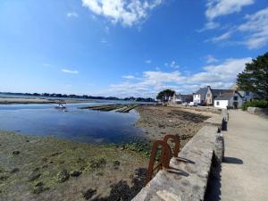 a bench sitting next to a body of water at Studio cosy proche bourg et plages tout équipé in Plouhinec