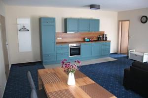 a kitchen with blue cabinets and a table with flowers at Am Wiesenblick 2 Pers in Röbel