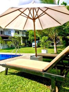 a bench with an umbrella next to a pool at Villa Shanthi in Dharga Town