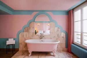 a bathroom with a bath tub and a stone wall at Hôtel Amour Paris in Paris