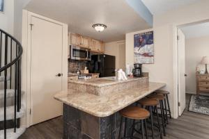a kitchen with a large stone counter top and stools at Summit Unit 1303 in Granby