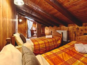 a bedroom with two beds in a room with wooden walls at Residence Les Myosotis in Champoluc