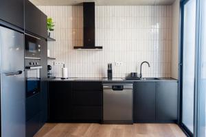 a kitchen with black cabinets and a stainless steel refrigerator at Essence Villas - Bath & Sunset in Ribeira Grande