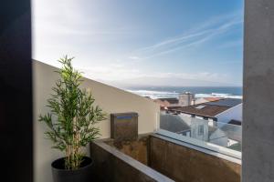 a view of the ocean from a balcony with a plant at Essence Villas - Bath & Sunset in Ribeira Grande