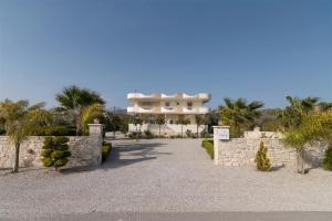 a large white house with palm trees and a driveway at Nerida Luxury Villas in Kastéllion