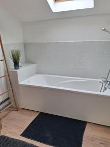 a white bath tub in a bathroom with a black rug at gite du montagnard in Oxelaere +17 photos