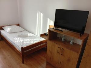 a small bedroom with a bed and a flat screen tv at ORION in Ostrów Mazowiecka