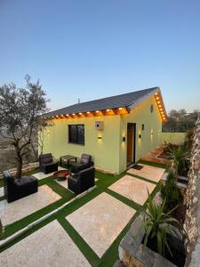 ein Haus mit Terrasse und Sofas im Garten in der Unterkunft Cherry farm in Adschlun