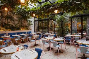 a restaurant with tables and chairs and plants at Hôtel Amour Paris in Paris