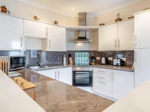 a large kitchen with white cabinets and appliances at Uk47549 - Carty Cottage in Newton Stewart
