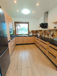 a large kitchen with wooden cabinets and a large window at Willa Kwiat Jabłoni in Mikołajki