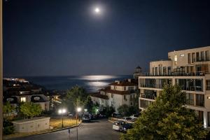 a view of a city at night with the moon at Sea Vista Hotel in Sveti Vlas