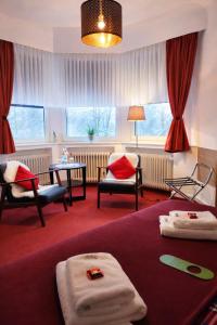 a hotel room with a bed and chairs and windows at Hotel Wappenhof in Braunlage