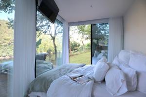 a bedroom with a bed with white pillows and a window at VILLA La Finca - Privada in Vieira do Minho