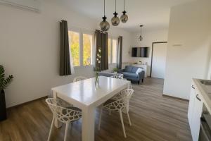a kitchen and living room with a white table and chairs at Lilly Garden Lago Lugano with private parking garden and air conditioning in Porlezza +7 photos