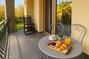 a table with a tray of croissants and fruit on a balcony at Lilly Garden Lago Lugano with private parking garden and air conditioning in Porlezza