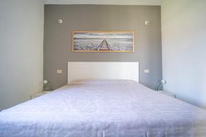 a bedroom with a white bed with a painting on the wall at La Cinta Apartments in San Teodoro